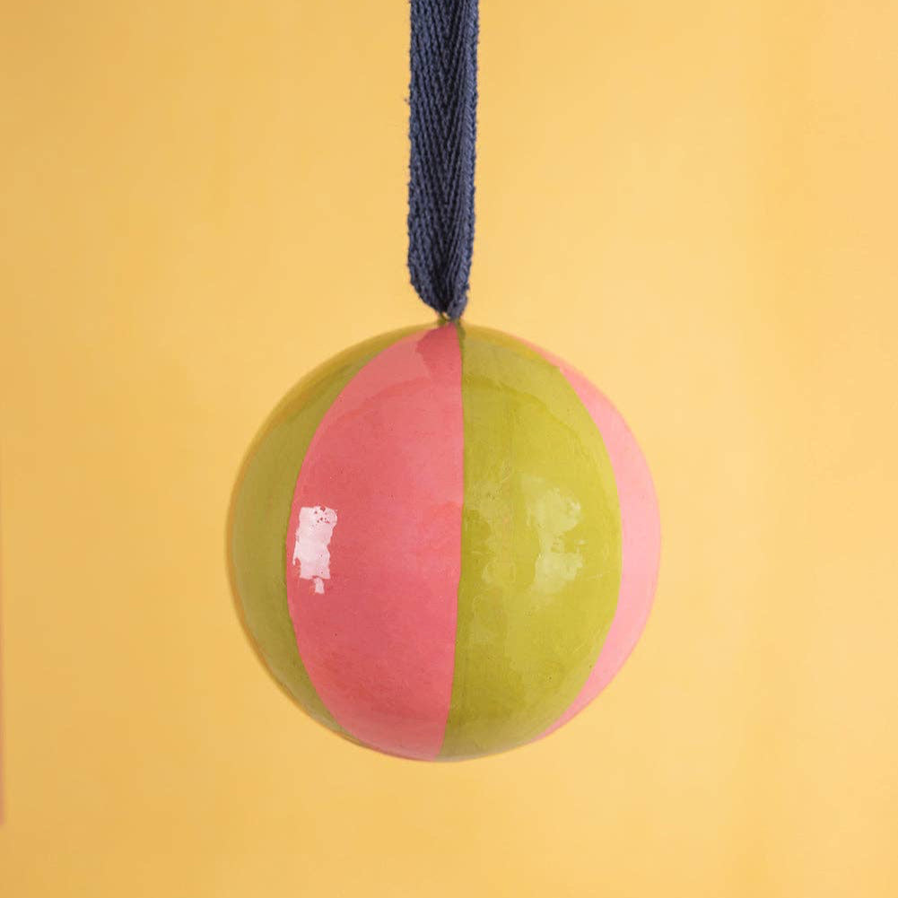 Two-toned pink and green ball with a blue rope on a yellow background
