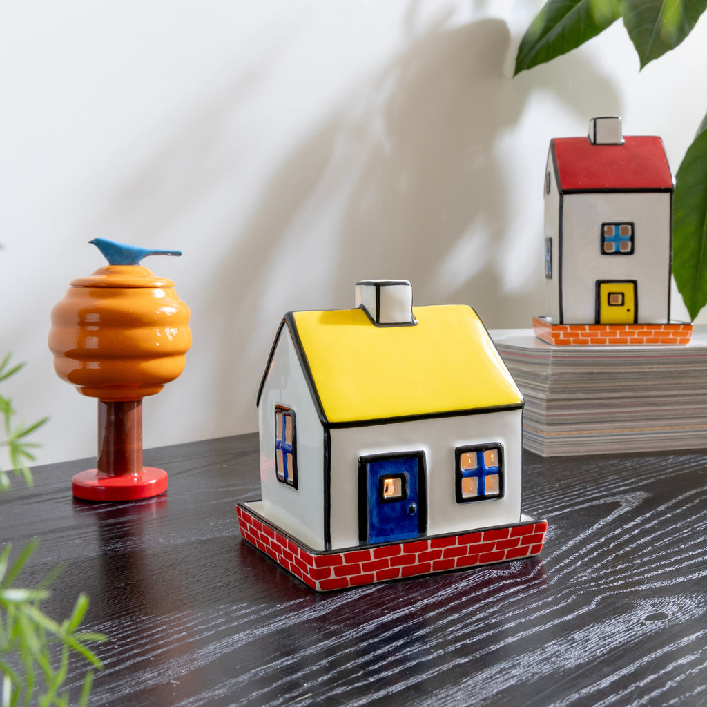 Decorative house models on a dark surface with greenery in the background