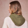 Person wearing a green knitted scarf on a beige background