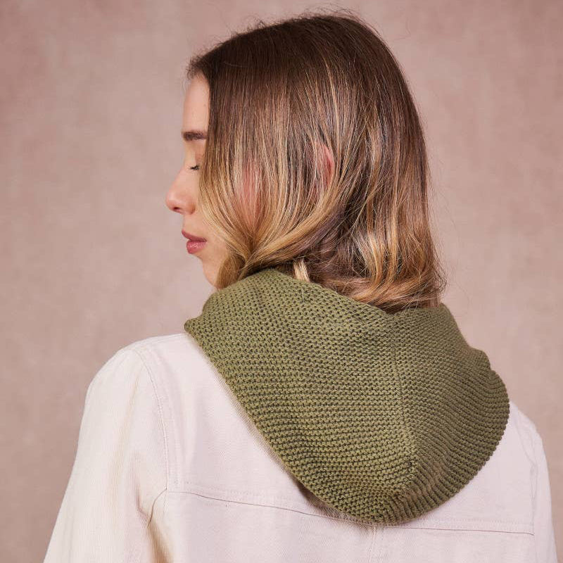 Person wearing a green knitted scarf on a beige background