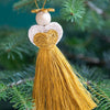 Decorative angel ornament with yellow fabric and white bead on a green tree branch