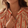 Close-up of a person wearing a floral blouse with jewelry and hair accessories.