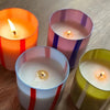 Four colorful striped candles on a wooden surface