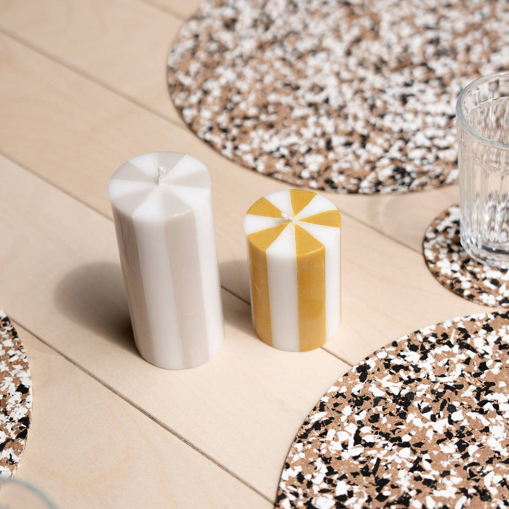 Decorative candles on a table with speckled coasters