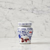 A glass jar of Amarena Fabbrica fruit and syrup, featuring a white label with blue floral patterns, German text, a red 'Gluten Free' badge, and an illustration of ice cream and dark red syrup.