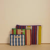 Three striped pouches with 'Bacca Bucci' branding on a beige background
