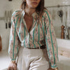 Woman wearing a floral blouse and white pants in a kitchen setting