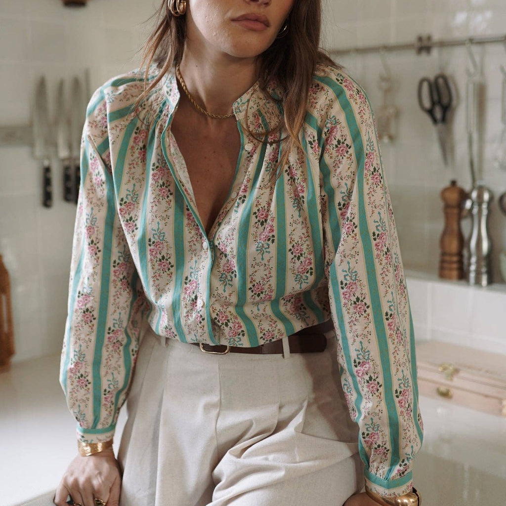 Woman wearing a floral blouse and white pants in a kitchen setting
