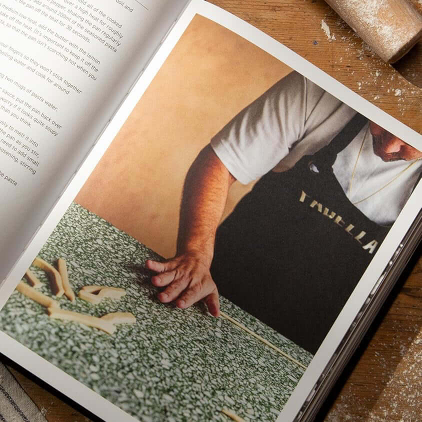 Open book on a wooden surface with a rolling pin and tomatoes