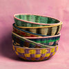 Stack of colorful woven baskets on a pink background