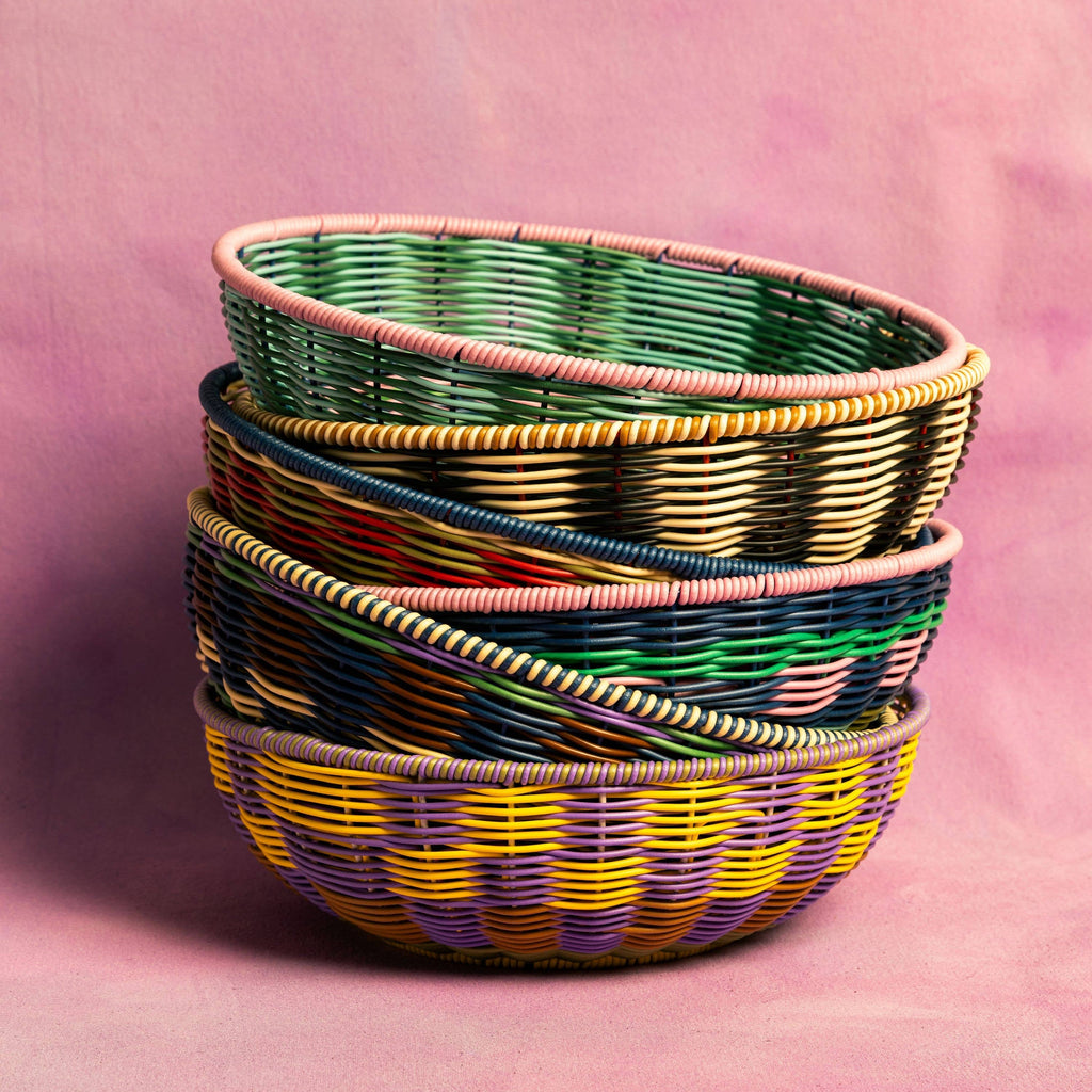 Stack of colorful woven baskets on a pink background