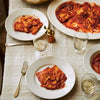 Dinner table set with plates of pasta, glasses of water, and a bowl of salad.