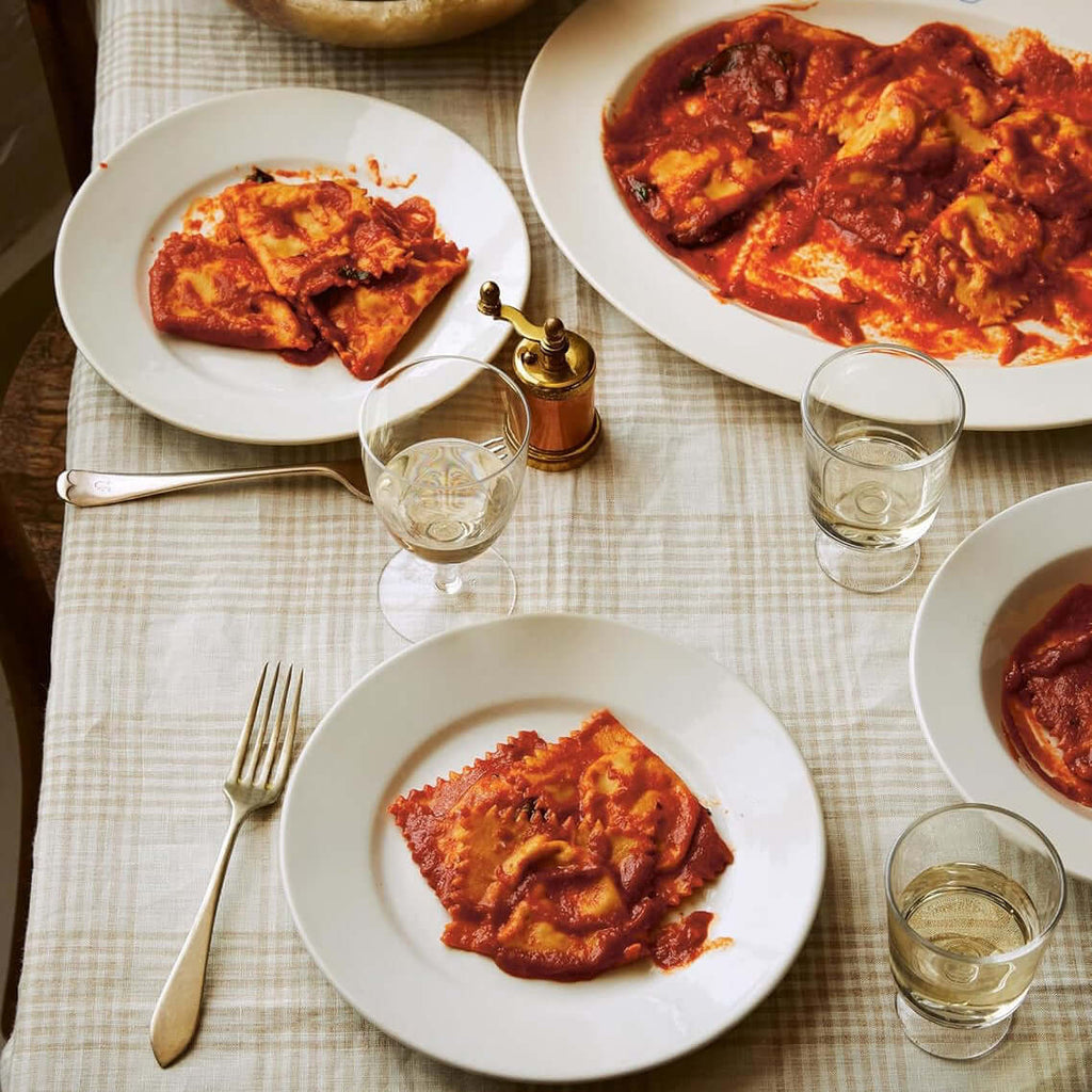 Dinner table set with plates of pasta, glasses of water, and a bowl of salad.