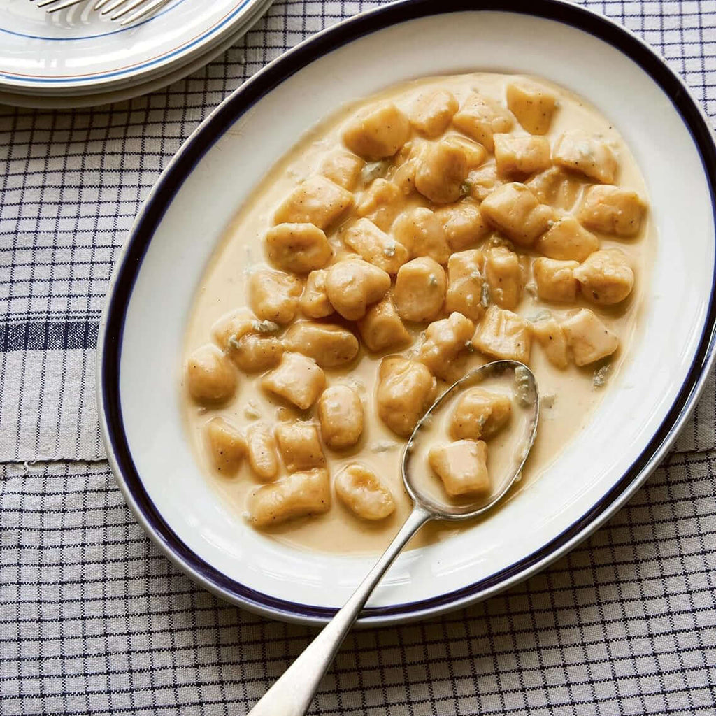 Plate of gnocchi with a creamy sauce on a checkered tablecloth