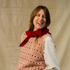 Woman wearing a patterned vest and red scarf against a plain background