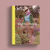 A book cover titled 'Garden People: Valerie Finnis and the Golden Age of Gardening' shown against a muted mauve background. The cover features a woman in a garden wearing a straw hat, green cardigan, lavender scarf, light blue top, and brown trousers, with a bright yellow vertical band on the left side.