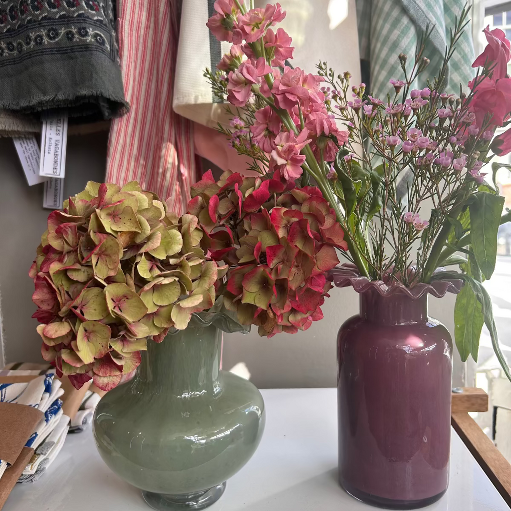 Two vases with flowers on a table in a store setting