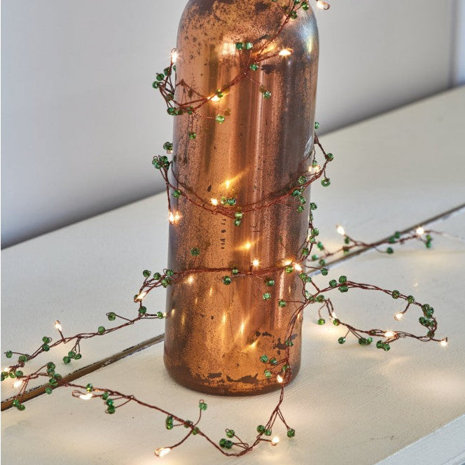 Decorative bottle with string lights on a white surface