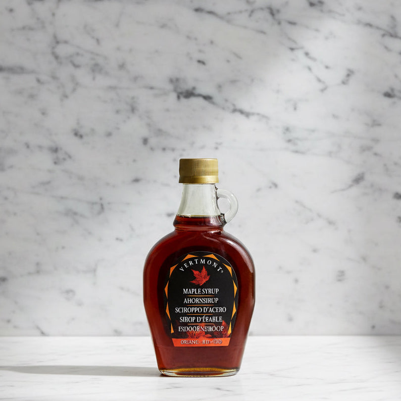 A bottle of Vermont Organic Bio-Zero maple syrup with a gold cap and a black label featuring a red maple leaf, set against a plain white background.