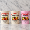Three plastic tubs of Fil di Chiaraвериni e C. fruit spread arranged on a white marble surface against a white marble background.