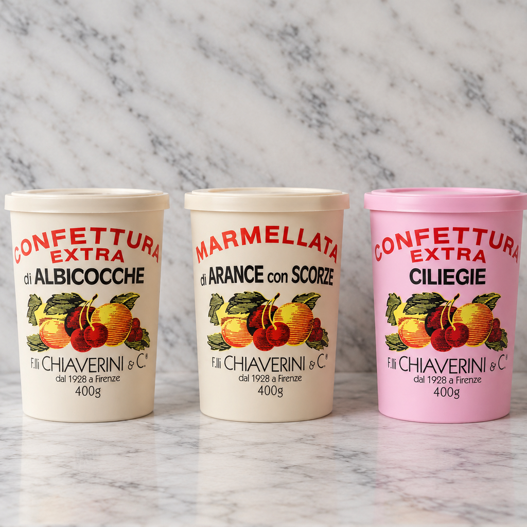 Three plastic tubs of Fil di Chiaraвериni e C. fruit spread arranged on a white marble surface against a white marble background.