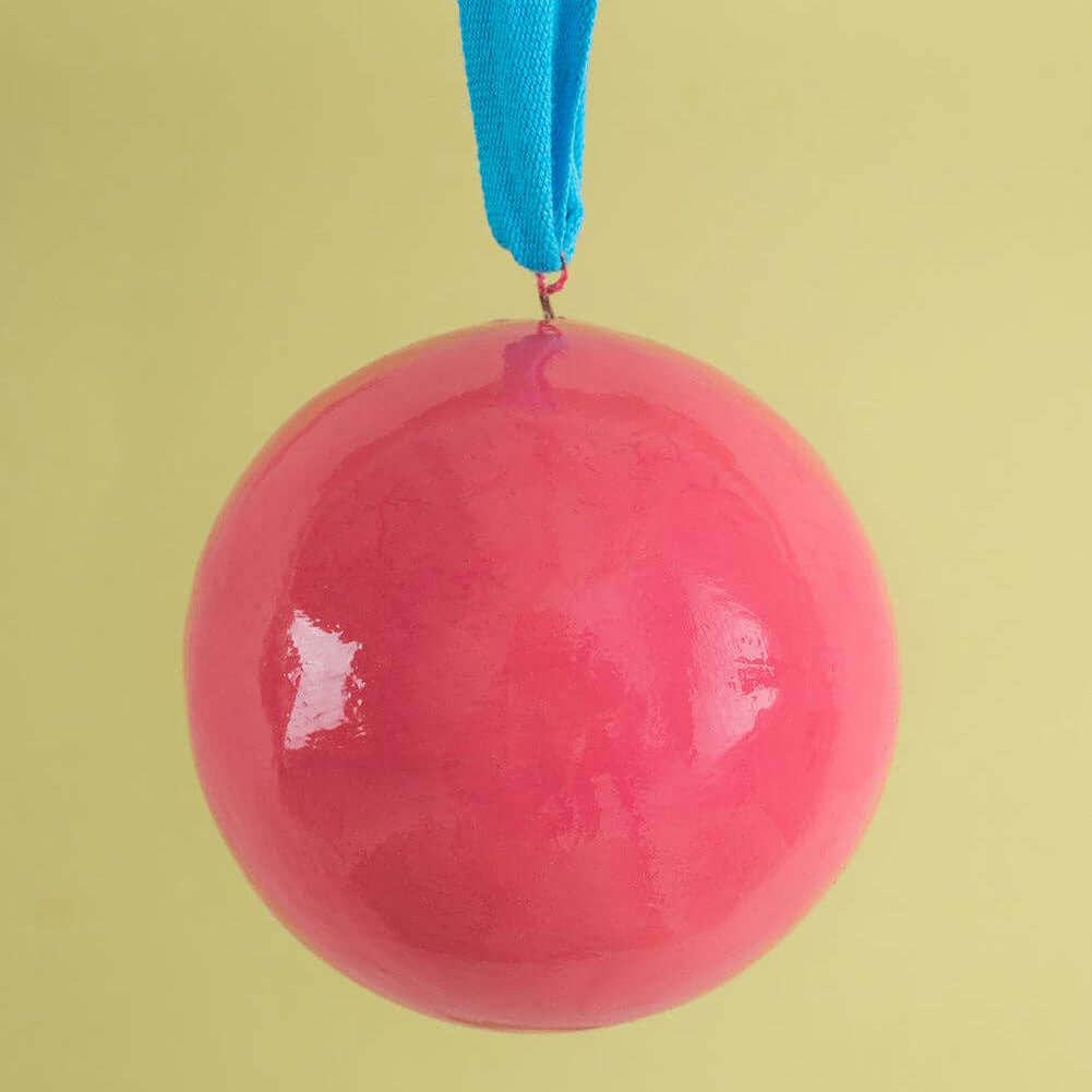 Pink ball hanging from a blue ribbon against a yellow background