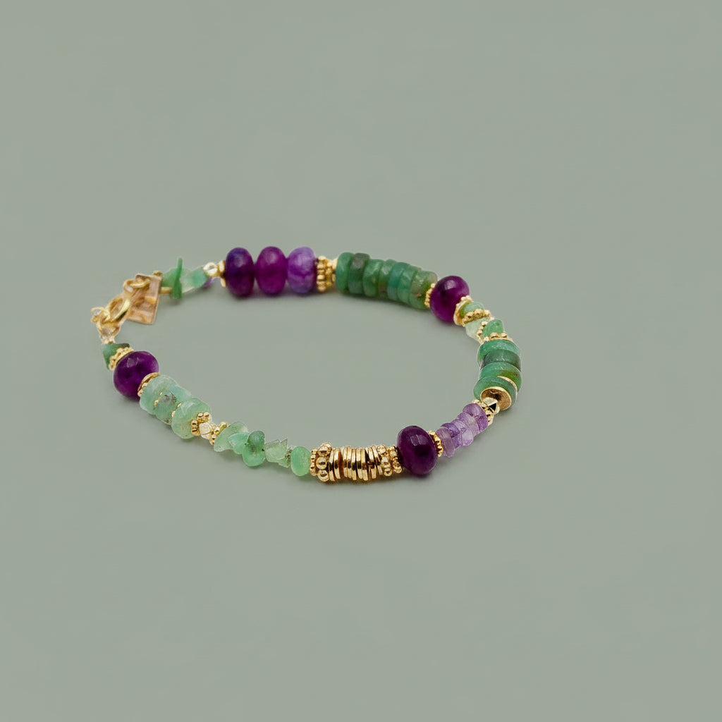 A beaded stretch bracelet featuring green and purple gemstone beads, gold spacer beads, and a gold clasp, displayed on a clean white background.