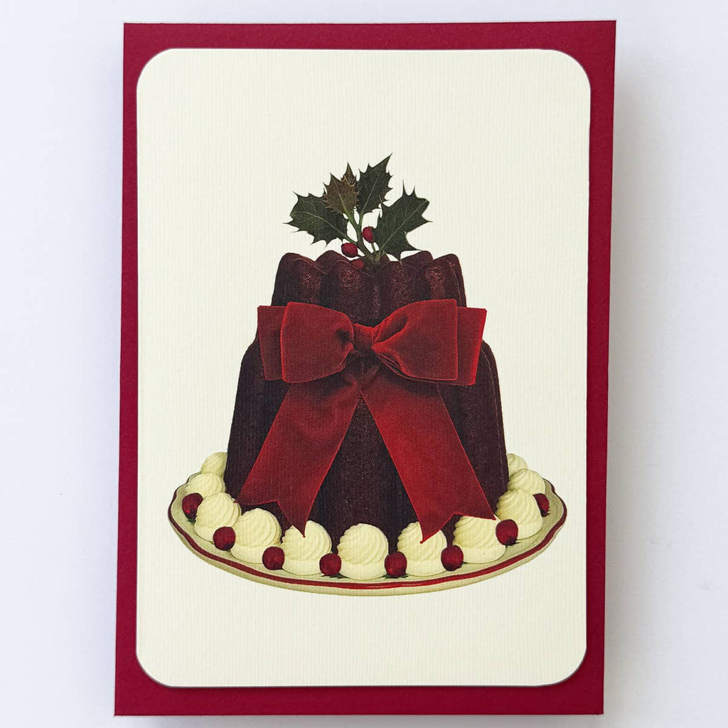 Card with a festive cake design featuring a red bow and holly on a white background
