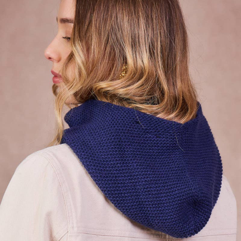 Woman wearing a blue knitted scarf against a beige background