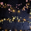 Decorative string lights with pink and white flowers on a dark background