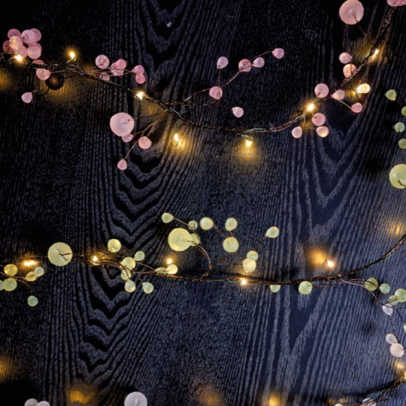 Decorative string lights with pink and white flowers on a dark background