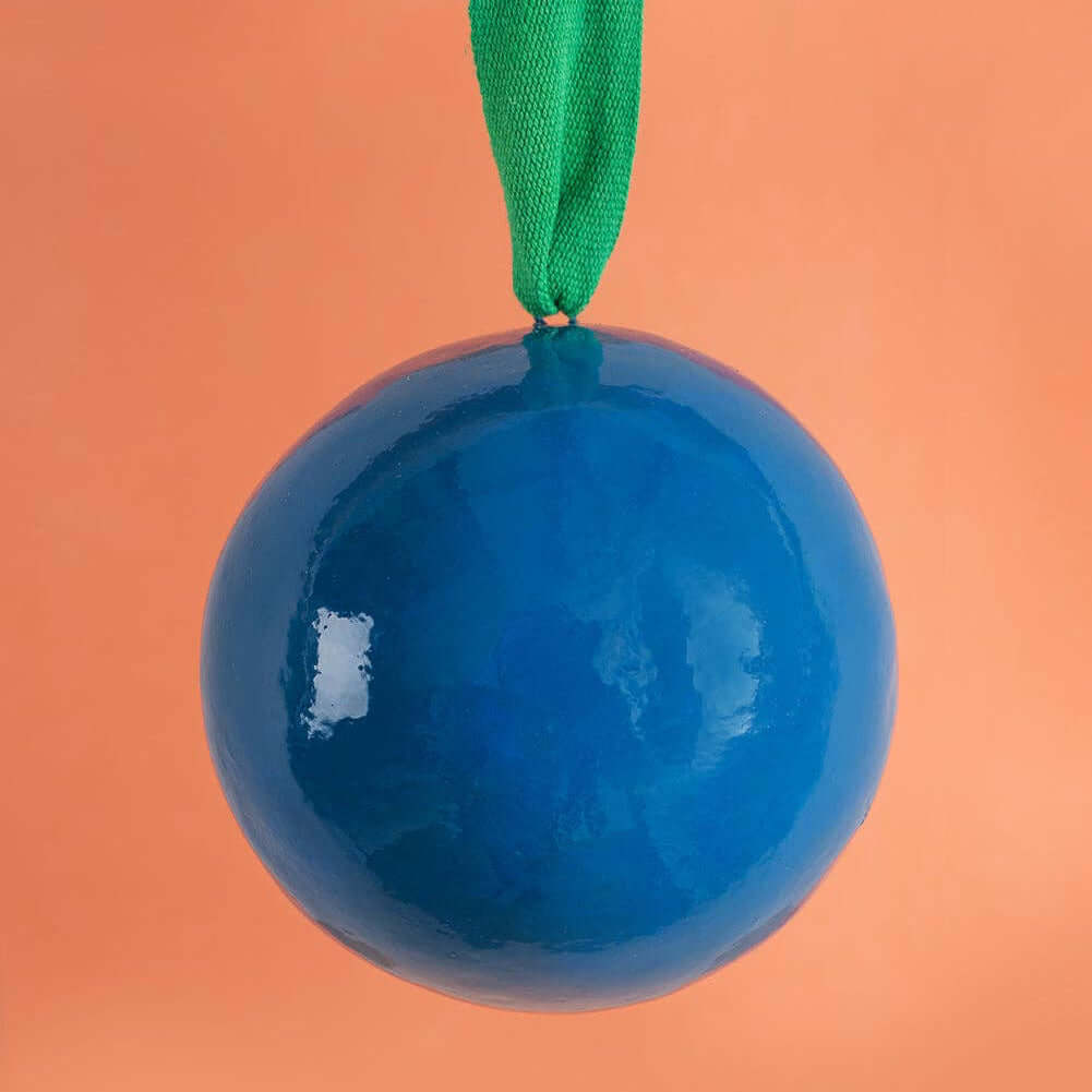 Blue ornament with a green ribbon on an orange background