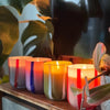 Colorful striped candles on a wooden surface with plants in the background