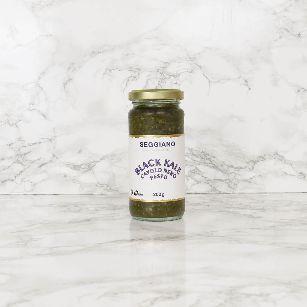 A jar of Seggiano Black Kale Pesto on a marble surface.