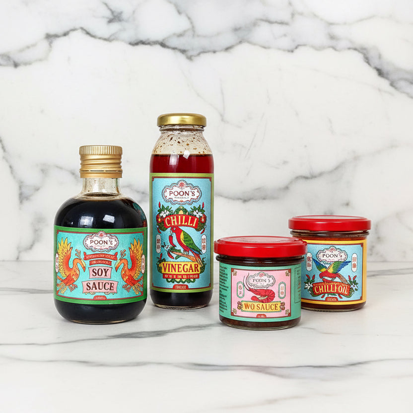 A collection of four bottled sauces on a wooden surface, with labels indicating the type of sauce, ranging from chili vinegar dressing to soy sauce.